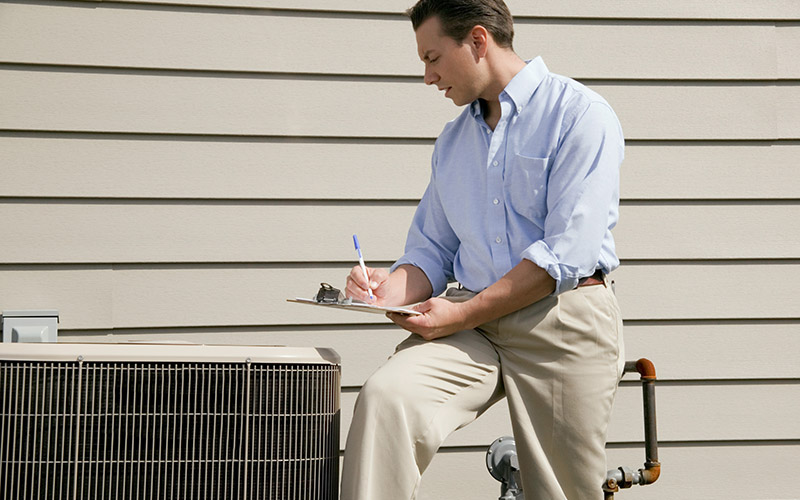 Man-with-clipboard-near-air-conditioning-unit
