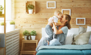 Happy Mother Holding Baby In Bed