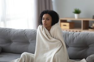 Woman Feeling Cold Wrapped In Blanket On Couch